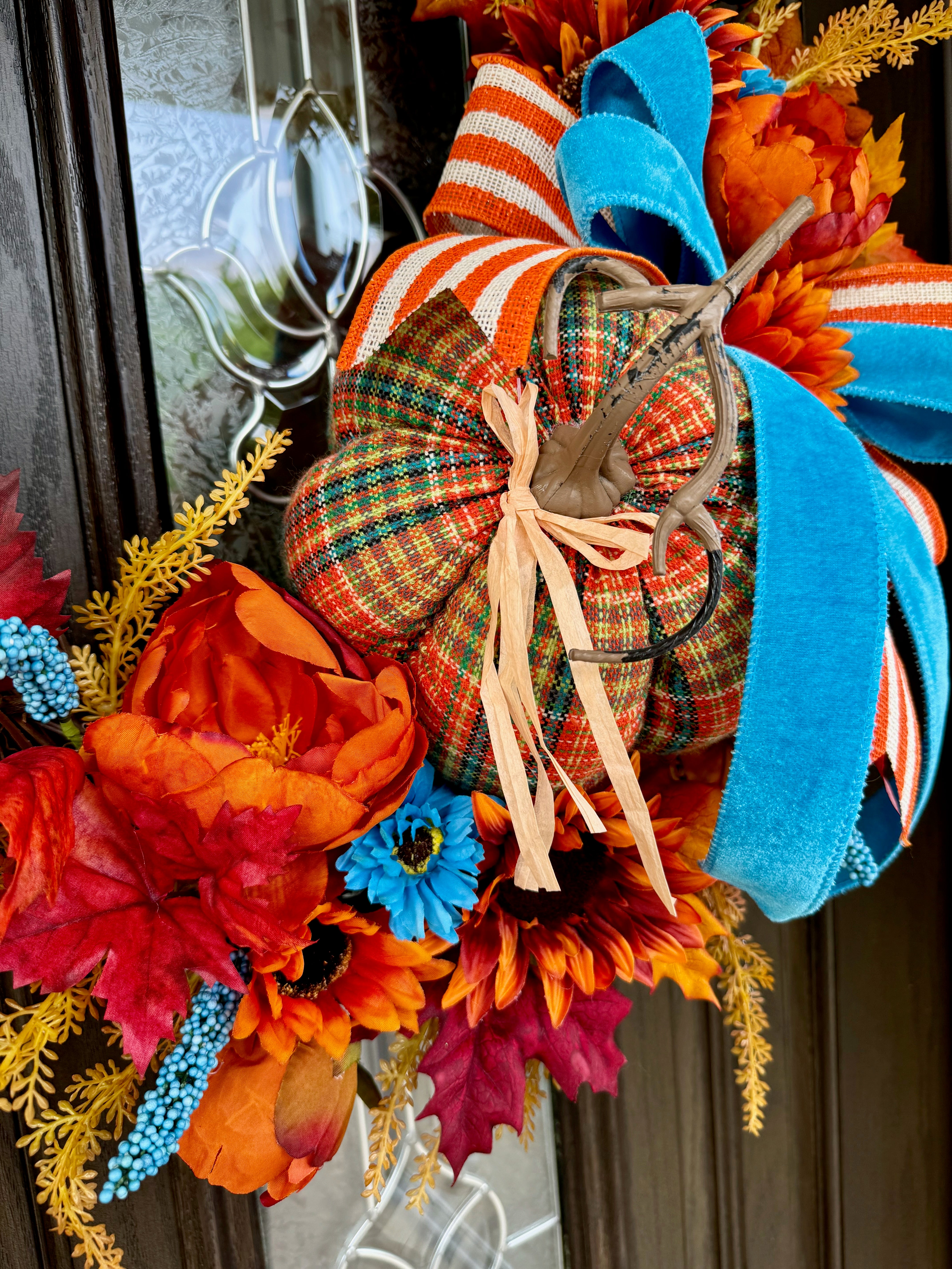 Fall Grapevine wreath orange ,white florals and blue berries with beautiful greenery. Adorned with beautiful popular ribbon and pumpkins .